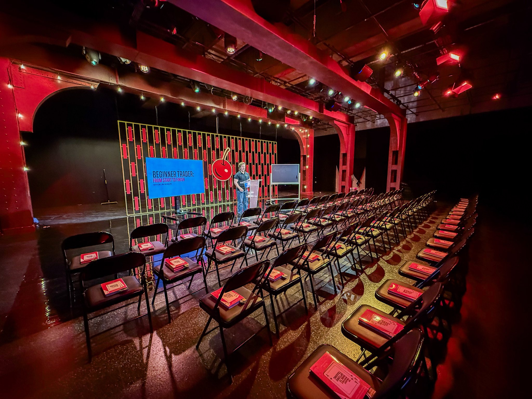 Theatre-style venue with red and blue lighting prepped for an audience