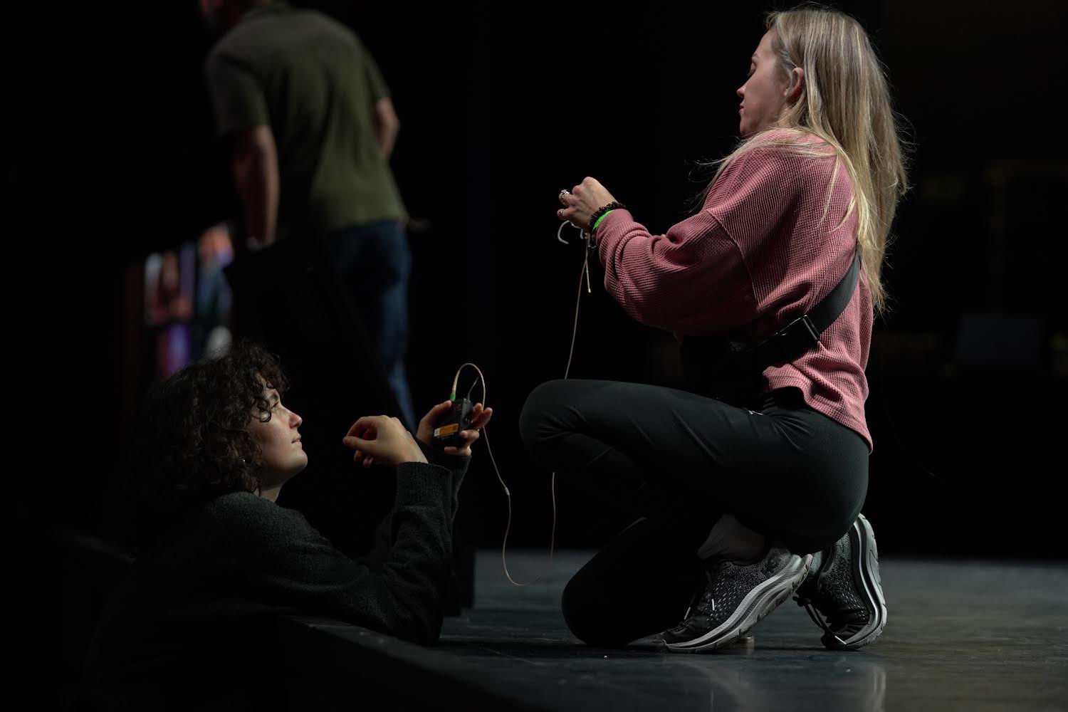 Production crew running mic checks on a darkened theater stage